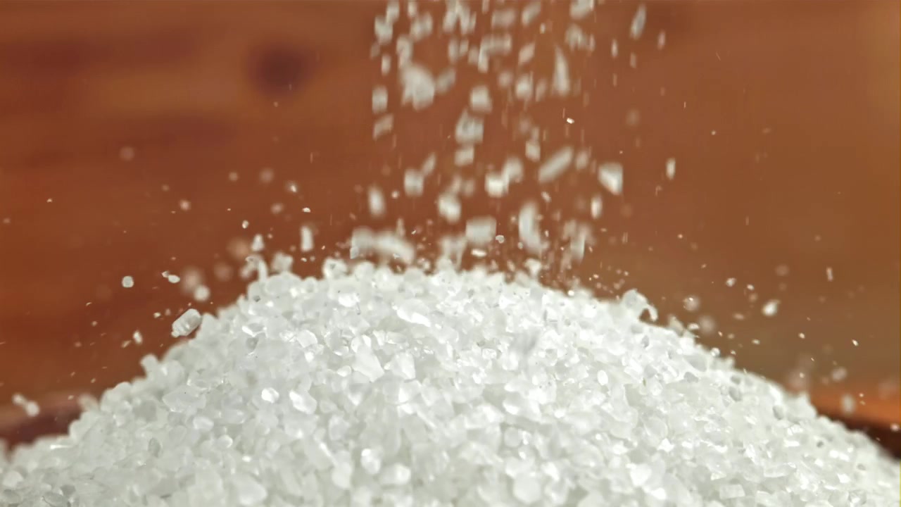 Cristais granulares brancos caindo sobre uma pilha em câmera lenta