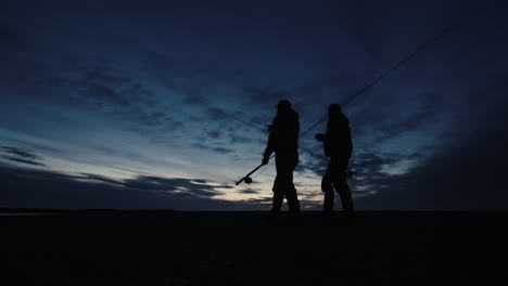 dos pescadores que van hacia el río para pescar con mosca durante el amanecer