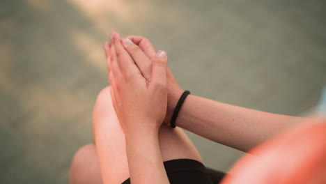 partial view of lady seated outdoor with leg crossed, hands resting on knee while gently rubbing palms together under warm sunlight, softly blurred background