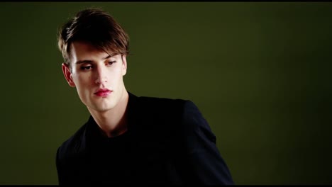 Androgynous-man-posing-with-sunglasses-against-green-background