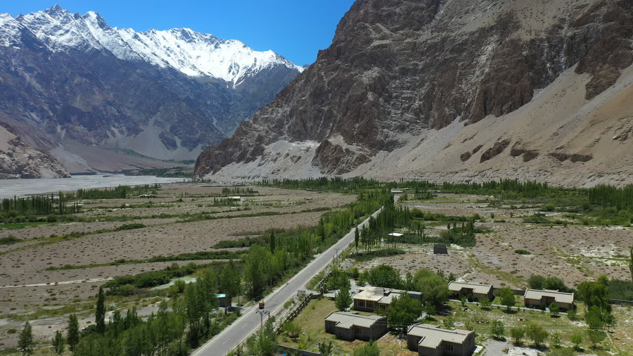 toma cinematográfica de drones de conos passu en hunza pakistán, moviéndose hacia el pico tupopdan con un tuk tuk conduciendo en la autopista karakoram, toma aérea amplia-1