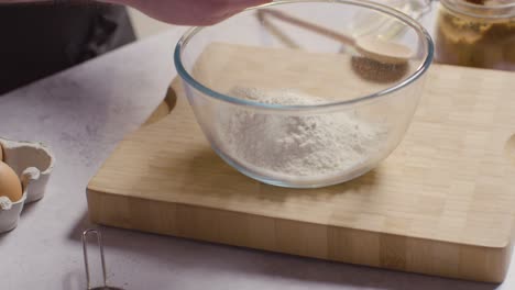 close up of man in kitchen at home adding ingredients to bowl to bake cake 3