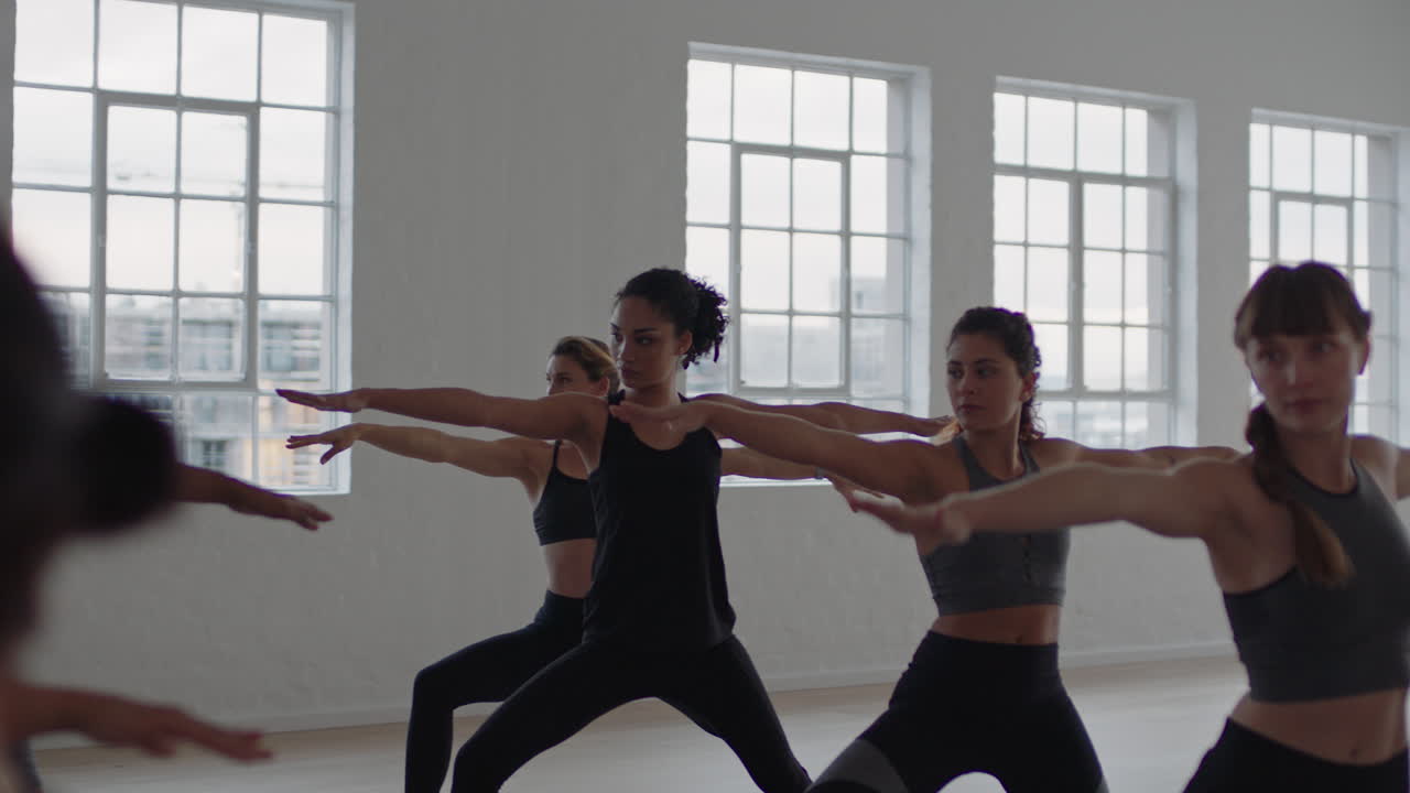 yoga class group of multiracial women practicing warrior pose enjoying healthy lifestyle exercising in fitness studio instructor teaching group meditation at sunrise