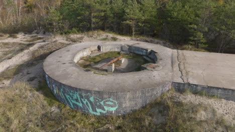 an aerial view of a defensive ww2 turret with preserved cannon on the coast of the baltic sea