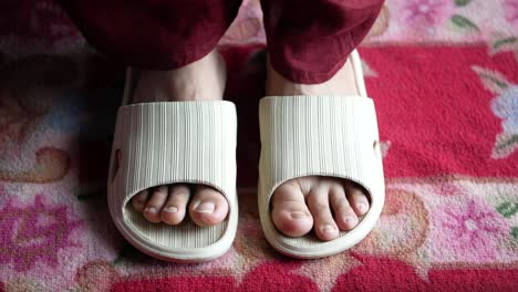 person wearing beige slippers on a patterned rug