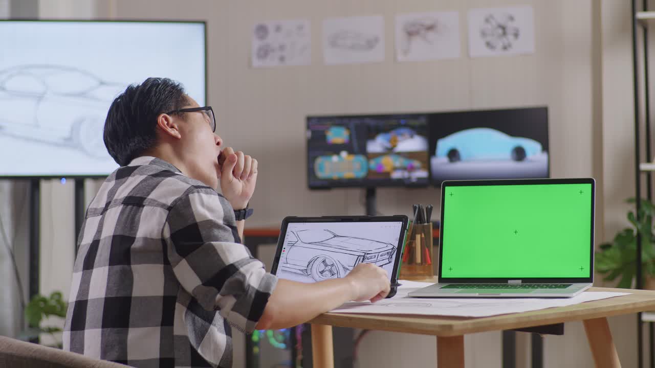 아시안 남성의 으로 보시면, 타블 에서 자동차 컨셉을 그리면서 잠을 자고, tv와 컴퓨터와 함께 스튜디오에서 녹색 화면 노트북을 표시하고, 3d 전기 자동차 모델을 표시합니다.