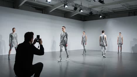 a contemporary fashion shoot captured in two frames: a photographer documenting the dynamic movement of models showcasing innovative designs on the runway
