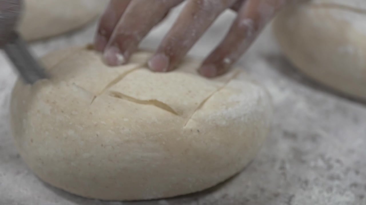 A woman rolling dough in a private bakery, captured in 4K resolution at 60fps, slow motion.