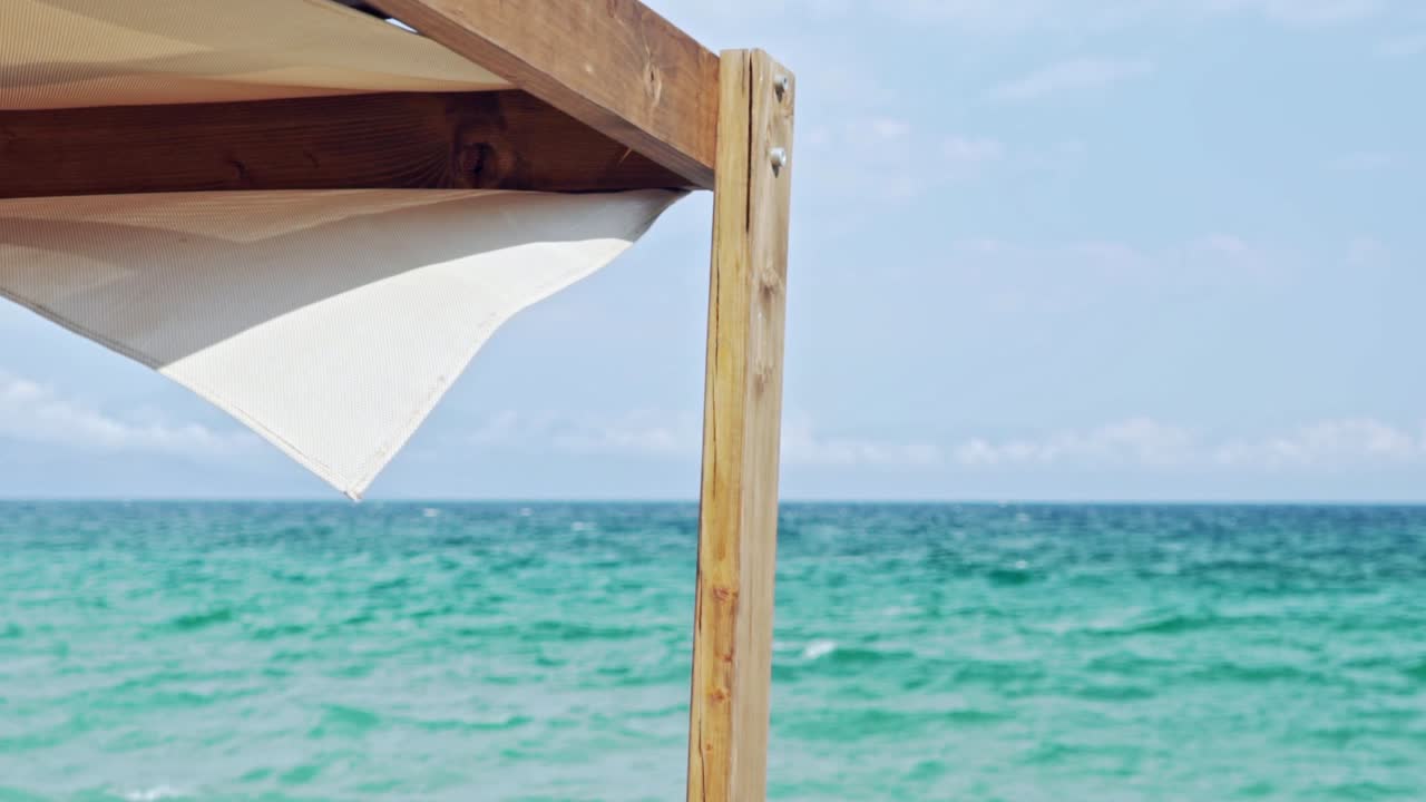 배경에 아름다운 녹색 바다가 있는 카바나 선베드의 일부, 얕은 필드 깊이, 느린 동작