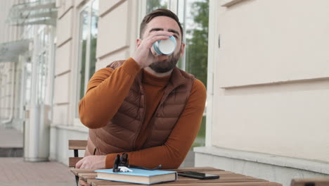 man drinking coffee at outdoor table