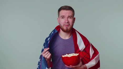 bearded young man basketball fan eating popcorn doing winner gesture, celebrating victory win