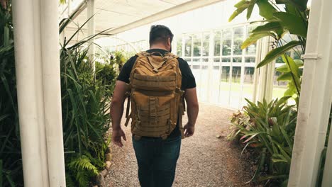 handheld shot of young male traveler with backpack walking through a brasilian tropical greenhouse