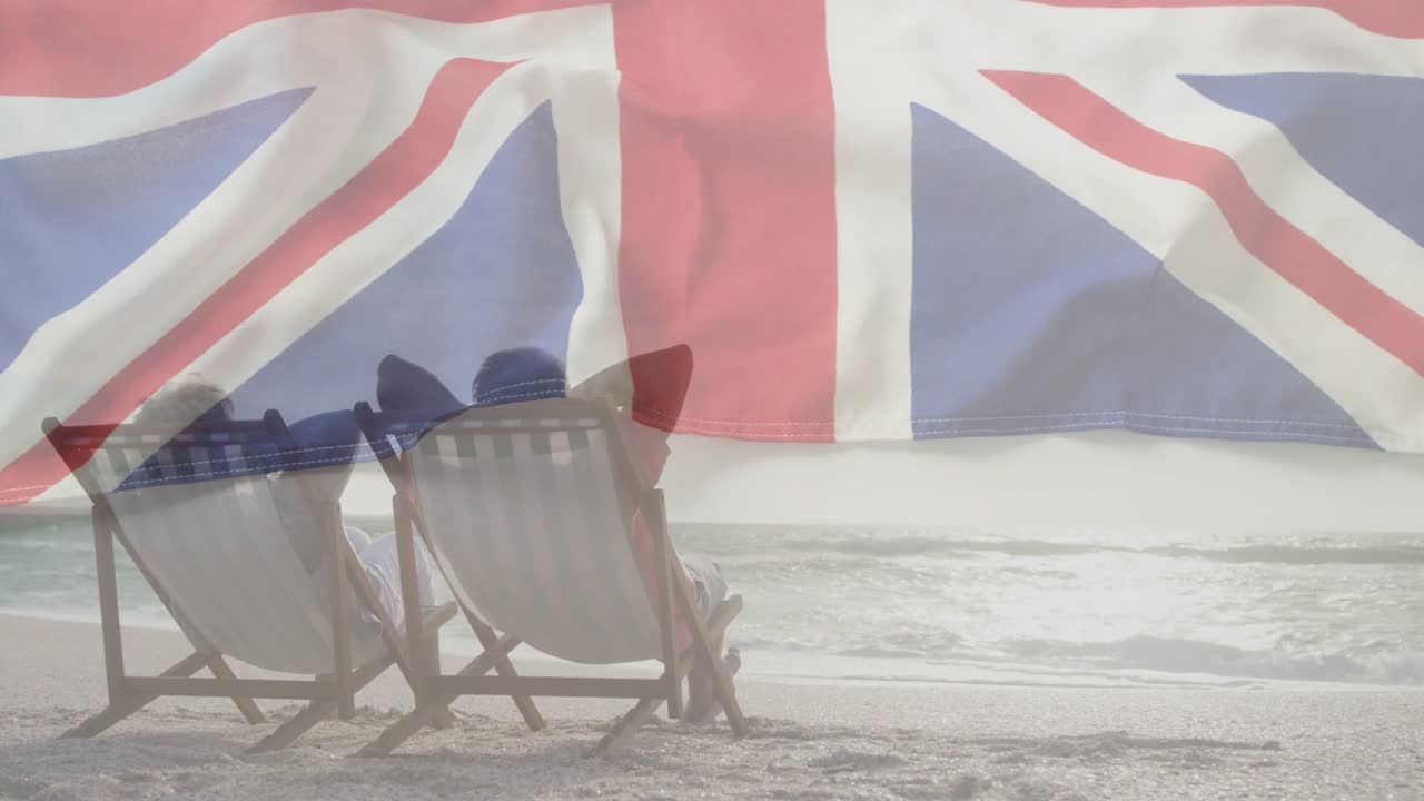 Coppia anziana seduta su sedie di fronte al mare, con animazione sovrapposta della Union Jack che sventola, promuovendo il turismo