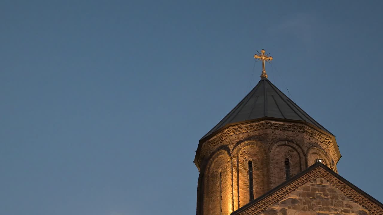 A peaceful evening view of Metekhi Church illuminated above the river in Tbilisi, capturing warm tones and the city's calm atmosphere
