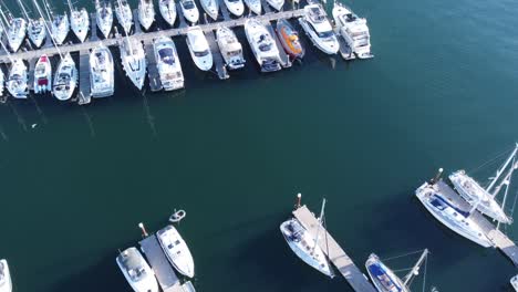 a forward flying drone shot of a marina and lots of boats, that slowly tilts up, revealing a beautiful harbour in the evening sun