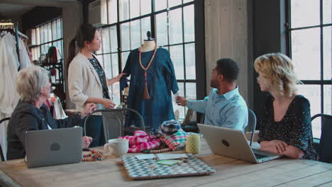 four fashion designers in meeting discussing garment