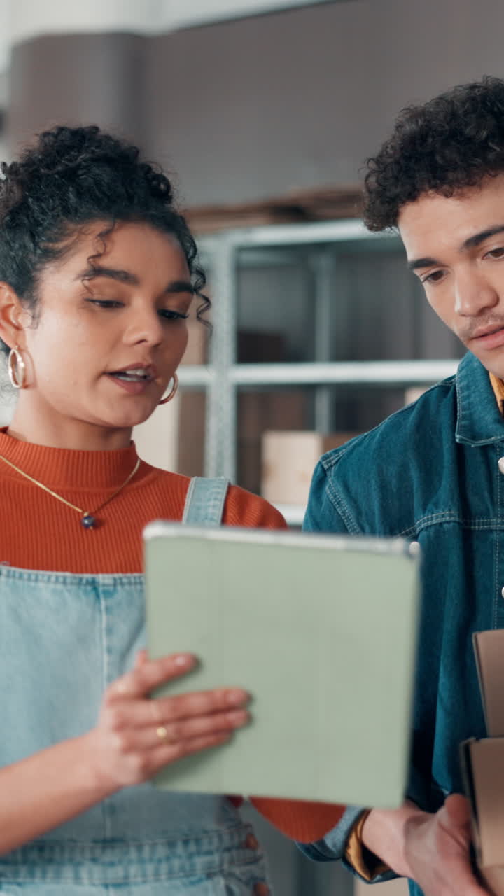 Jóvenes socios hablando de pedidos con una tableta y cajas