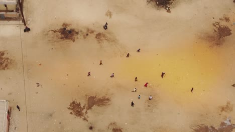 Aerial-zenith-shot-of-african-children-playing-football-on-the-sand