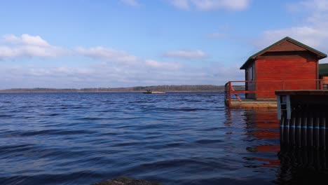 small camping wooden cabin on raft float on calm blue water lake, latvia