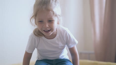 little girl in t-shirt jumps in playpen in children room