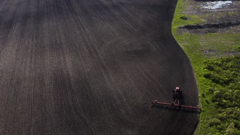 Aerial-shot-of-tractor-cultivating-large-unplanted-field