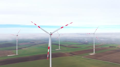 rotating wind turbines over misty rural farmlands