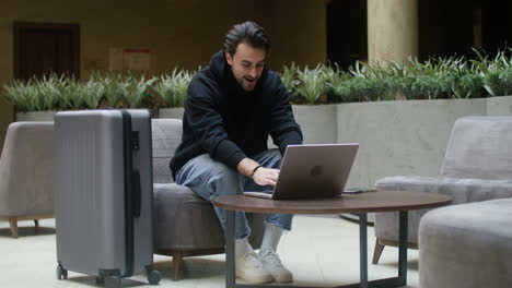 hombre usando una computadora portátil en el pasillo del hotel