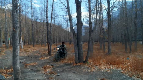 front view of solo motorbiker cruising and exploring high altitude forest area during autumn under himalayas