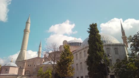 daytime, under partly cloudy skies, cinematic slow-mo, hagia sophia mosque with its minarets and a few trees in the foreground