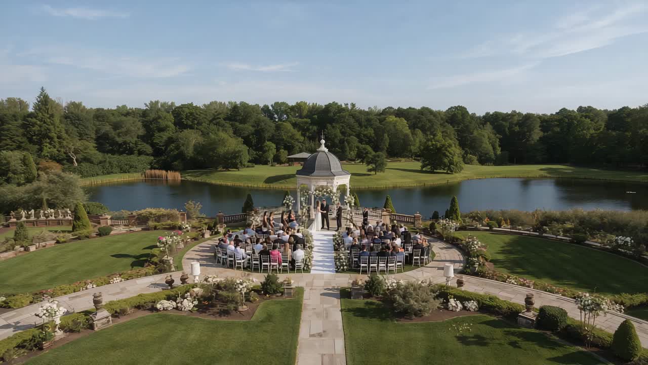 Drone revealing couple and officiant taking vows to marry at lakeside gazebo, bride in gown