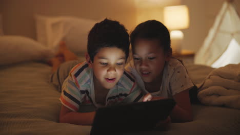 siblings watching tablet in bed at night