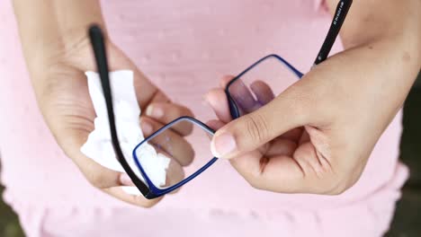 cleaning eyeglass with tissue close up