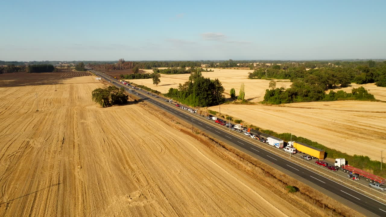Traffic On The Road Through Farmlands After The Accident Scene In Chile, South America. Aerial Pullback Shot