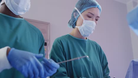 Video-of-asian-female-surgeon-at-work-during-operation-in-theatre-and-colleagues-passing-instruments