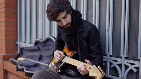 Man-playing-on-the-guitar-with-a-pick-outdoor