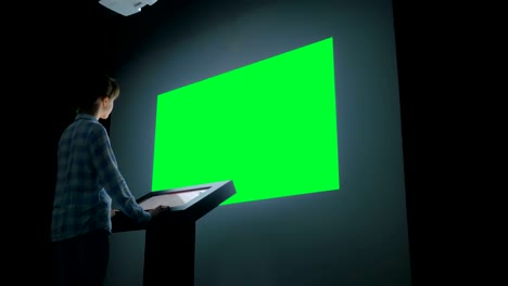 woman looking at blank large interactive wall display - green screen concept