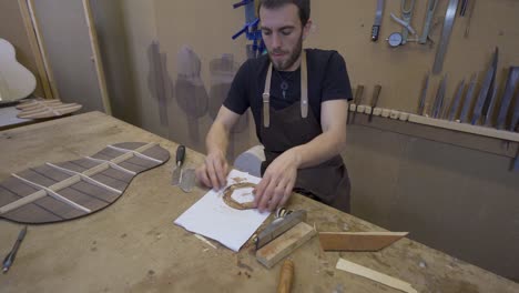 artesano aplanando una pieza de madera con un raspador en el taller