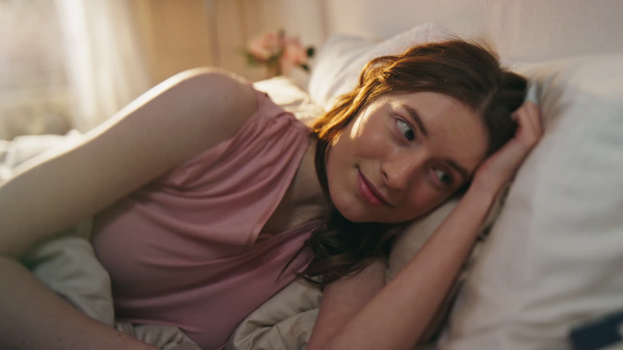 una mujer hermosa despertando por la mañana en primer plano. una chica sorprendida desempaquetando una caja de regalos.