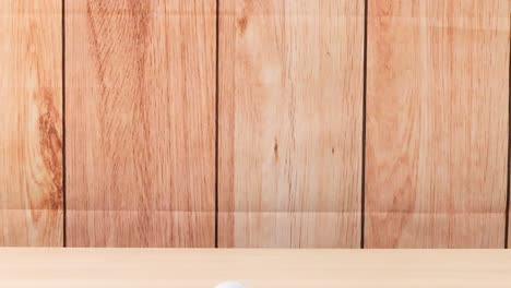 una pelota de golf se mueve a través de un piso de madera