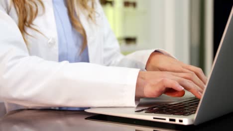 optometrista que usa una computadora portátil en una clínica oftalmológica