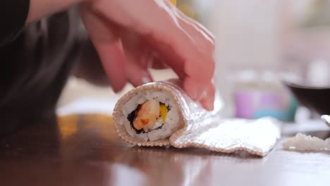 hacer sushi en la cocina de casa. manos de mujer enrollando sushi casero.