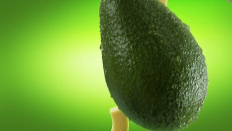 avocado with slices falling on green background