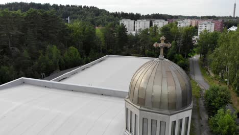 aerial flying around a small metal bell tower with cross on top in sweden