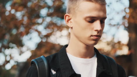 young student walking and using mobile phone outdoors.