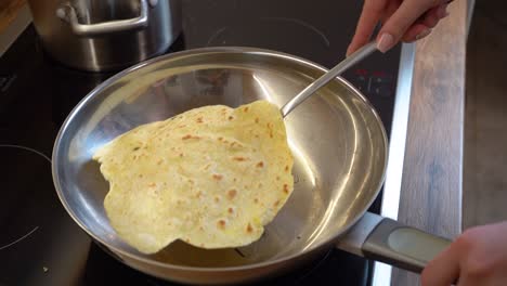 flipping a slice of tortilla in a frying pan with spatula