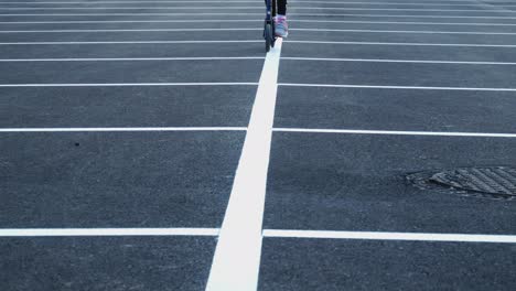 Ein-Mädchen-Fährt-Mit-Einem-Roller-Durch-Einen-Leeren-Parkplatz-1