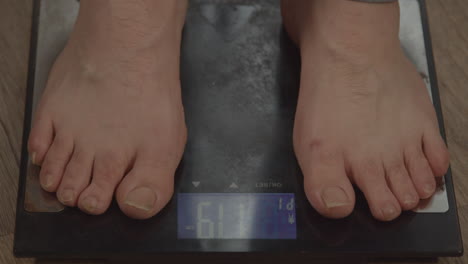 close up of bare feet stepping on weight scale