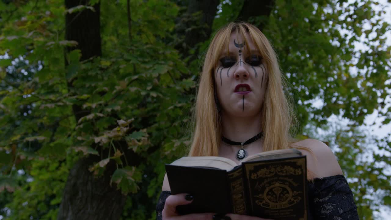 Beautiful Witch smiling in an evil way to the camera and turning around in the cemetery, slow motion Close up