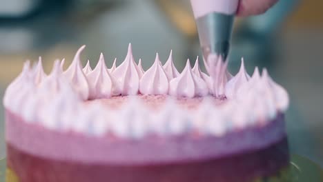 confectioner fills flat top of pink cake with white cream