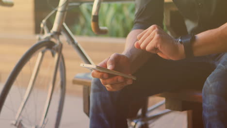 animación de un hombre biracial sentado y usando un teléfono inteligente con una bicicleta